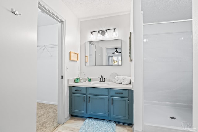 bathroom featuring hardwood / wood-style floors, vanity, a textured ceiling, and walk in shower