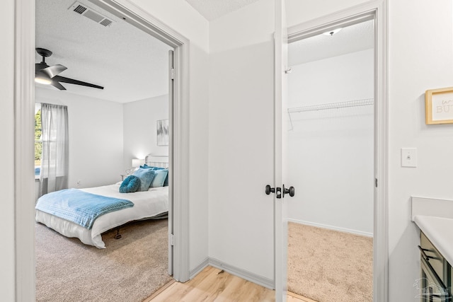 bedroom featuring ceiling fan, a closet, a textured ceiling, and light hardwood / wood-style flooring