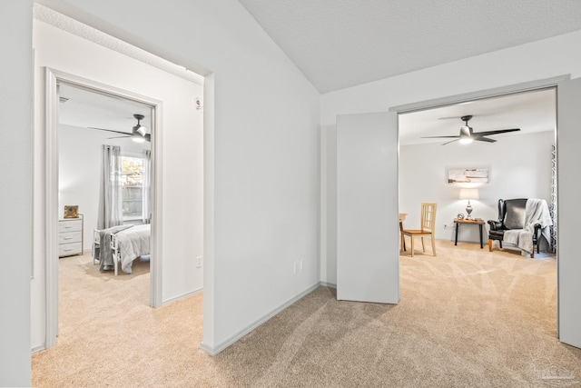 corridor featuring vaulted ceiling, light colored carpet, and a textured ceiling