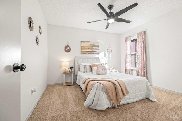 bedroom featuring a textured ceiling, light colored carpet, and ceiling fan