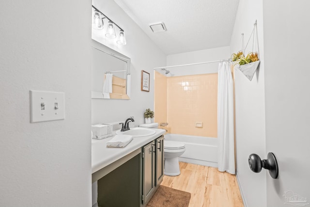 full bathroom featuring wood-type flooring, a textured ceiling, toilet, shower / bath combo with shower curtain, and vanity