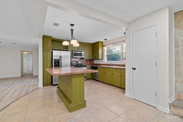 kitchen featuring stainless steel appliances, green cabinetry, a kitchen island, and visible vents