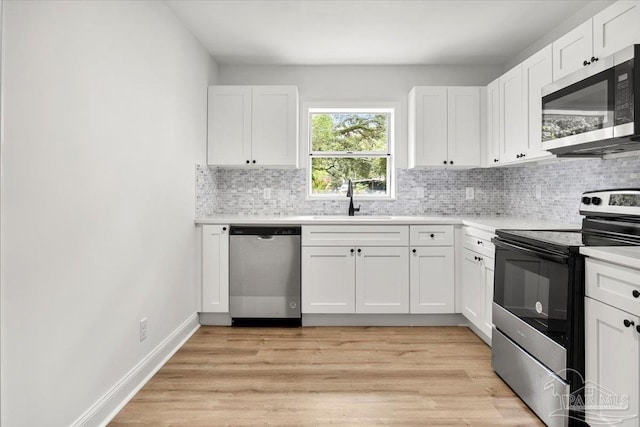 kitchen with stainless steel appliances, white cabinets, sink, backsplash, and light wood-type flooring