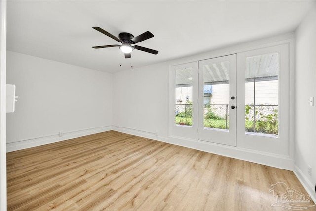 spare room featuring french doors, a healthy amount of sunlight, ceiling fan, and light wood-type flooring