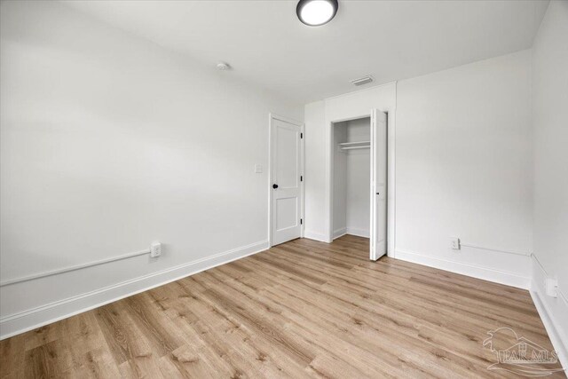 unfurnished bedroom with a closet and light wood-type flooring