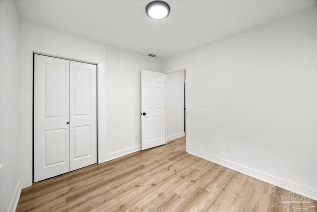 unfurnished bedroom featuring a closet and light wood-type flooring