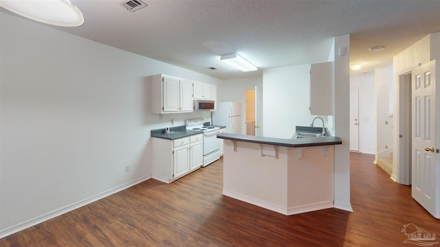 kitchen featuring dark wood-style flooring, visible vents, a sink, white appliances, and a kitchen breakfast bar