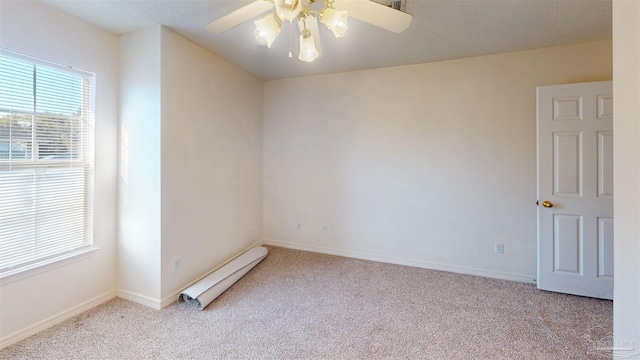 empty room featuring carpet floors, a baseboard radiator, a ceiling fan, and baseboards