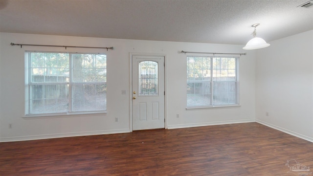 doorway to outside with a textured ceiling, wood finished floors, visible vents, and baseboards