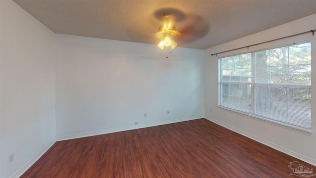 spare room with dark wood-style floors, a ceiling fan, baseboards, and a textured ceiling