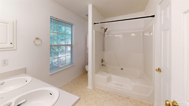 full bathroom with toilet, double vanity, a sink, and tile patterned floors