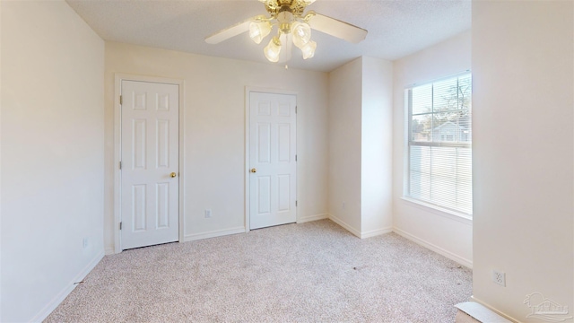 unfurnished bedroom with carpet floors, a textured ceiling, baseboards, and a ceiling fan