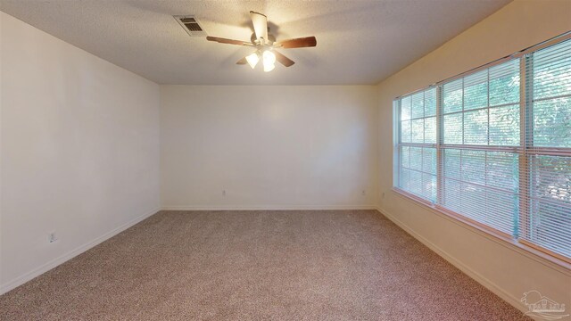 unfurnished room with visible vents, light colored carpet, ceiling fan, a textured ceiling, and baseboards