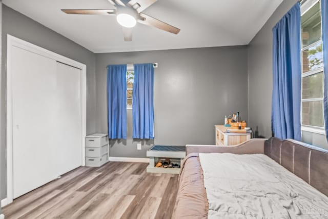 unfurnished bedroom with a closet, hardwood / wood-style flooring, multiple windows, and ceiling fan