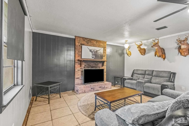 living room featuring crown molding, a fireplace, light tile patterned floors, and a textured ceiling