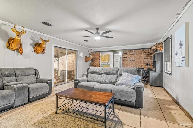 tiled living room featuring a textured ceiling, a wood stove, ceiling fan, and crown molding