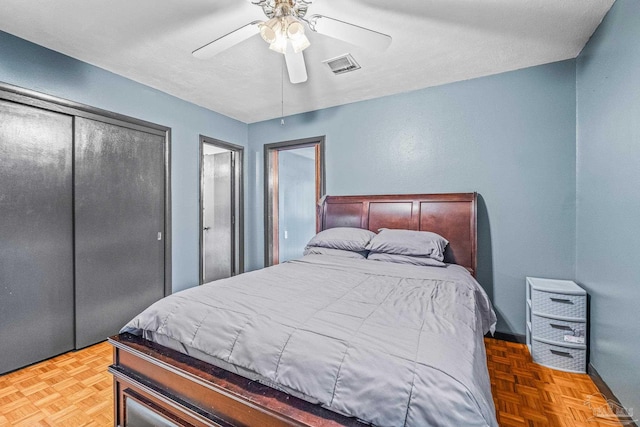 bedroom featuring ceiling fan, a closet, parquet floors, and a textured ceiling