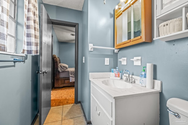 bathroom featuring vanity, toilet, parquet flooring, and a textured ceiling