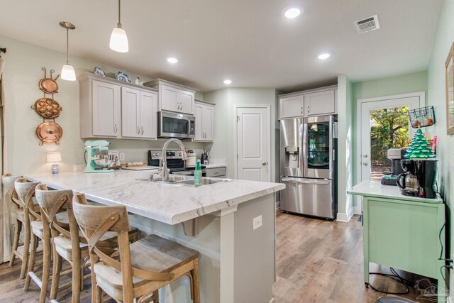 kitchen featuring sink, hanging light fixtures, stainless steel appliances, kitchen peninsula, and white cabinets