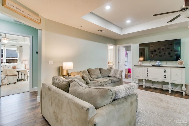 living room featuring hardwood / wood-style floors and a tray ceiling