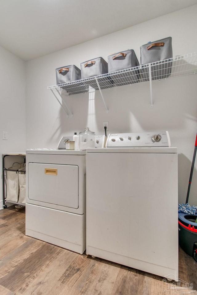 laundry room with washing machine and dryer and light hardwood / wood-style floors