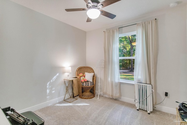 sitting room featuring radiator, ceiling fan, and light colored carpet