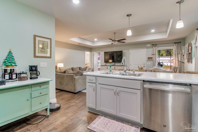 kitchen with stainless steel dishwasher, a raised ceiling, sink, and hanging light fixtures