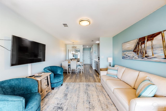 living room featuring light hardwood / wood-style flooring and an inviting chandelier