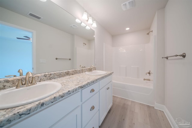 bathroom with vanity, hardwood / wood-style flooring, and washtub / shower combination