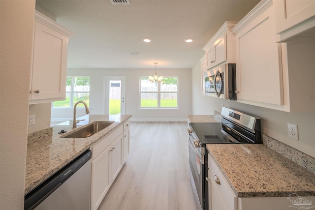 kitchen with stainless steel appliances, white cabinetry, sink, and light stone counters