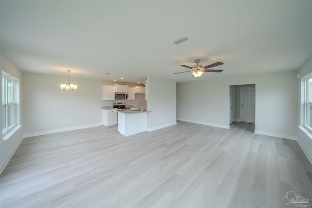 unfurnished living room with sink, ceiling fan with notable chandelier, and light hardwood / wood-style flooring