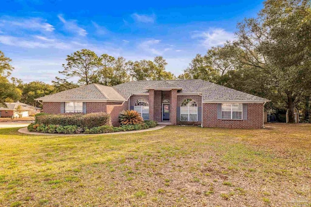 ranch-style house with a shingled roof, brick siding, and a front lawn