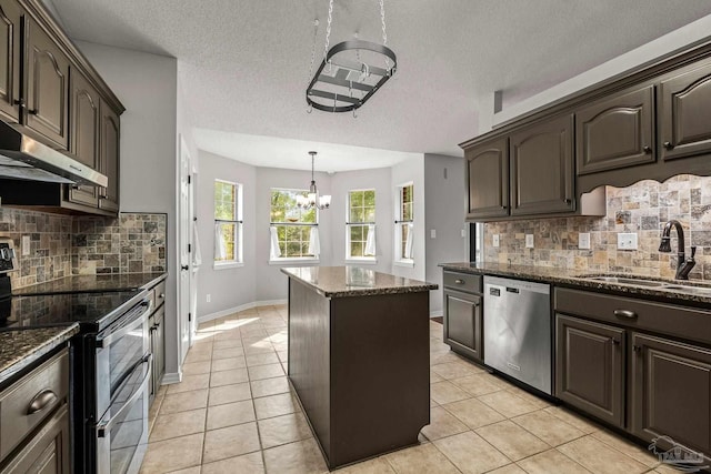 kitchen featuring a center island, stainless steel appliances, a sink, dark stone counters, and under cabinet range hood