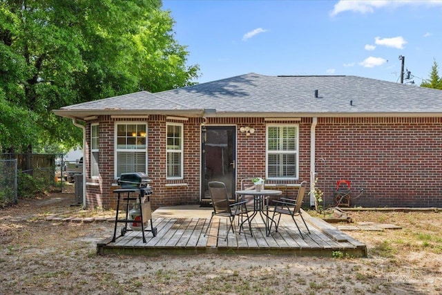 back of property featuring fence, a deck, and brick siding