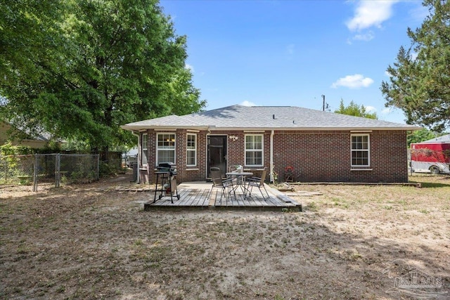 back of property with fence, brick siding, and a wooden deck