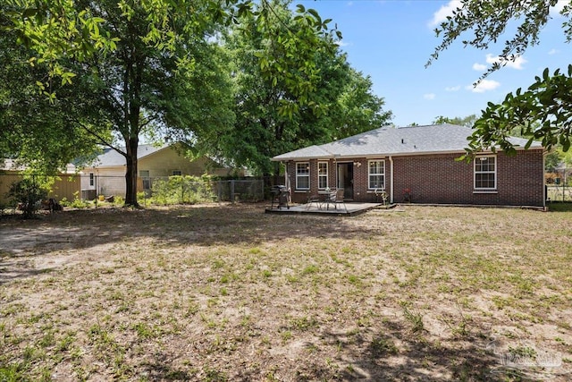 rear view of property featuring a patio, brick siding, fence private yard, and a lawn