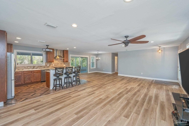 4900 Shell Rd, Milton, FL 32583 - kitchen with brown cabinetry, visible vents, stainless steel appliances, a kitchen bar, and wall chimney exhaust hood