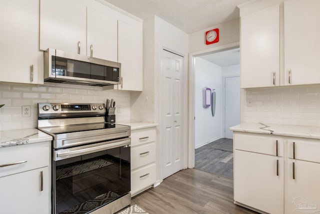 5945 Pamela Dr, Milton, FL 32570 - kitchen featuring stainless steel appliances, backsplash, light wood-style floors, white cabinetry, and light stone countertops