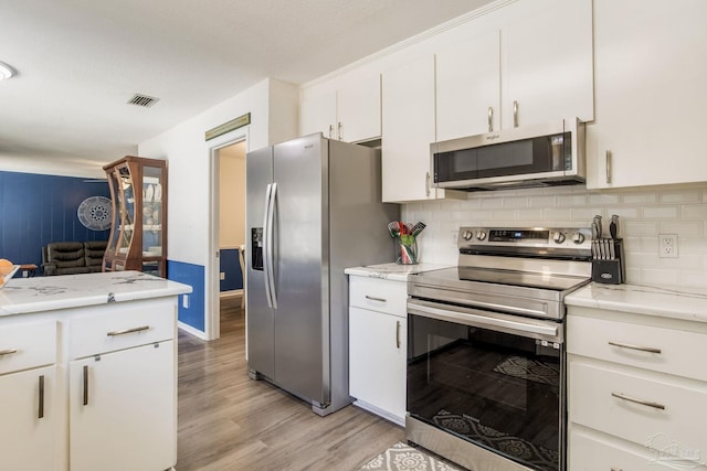5945 Pamela Dr, Milton, FL 32570 - kitchen with appliances with stainless steel finishes, light wood-style floors, decorative backsplash, white cabinets, and light stone countertops