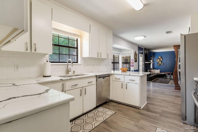 5945 Pamela Dr, Milton, FL 32570 - kitchen with stainless steel dishwasher, a sink, a peninsula, decorative backsplash, and light wood-type flooring