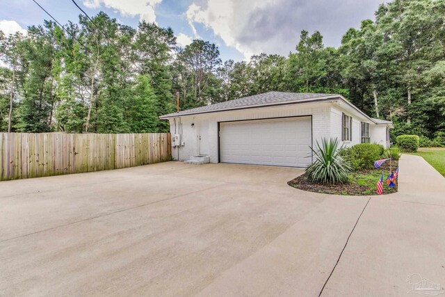 5945 Pamela Dr, Milton, FL 32570 - view of property exterior featuring brick siding, a garage, and view of wooded area