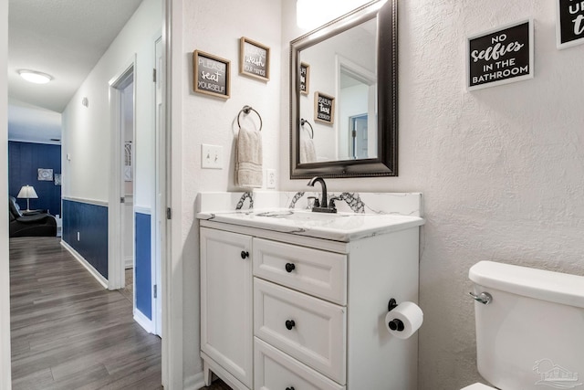 5945 Pamela Dr, Milton, FL 32570 - bathroom with vanity, wood finished floors, toilet, a textured wall, and baseboards