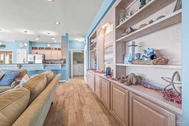 interior space featuring built in shelves, independent washer and dryer, and light hardwood / wood-style flooring