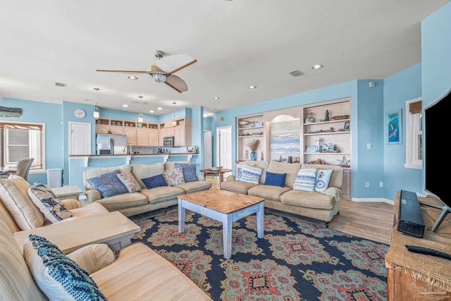 living room featuring hardwood / wood-style flooring, ceiling fan, and built in features