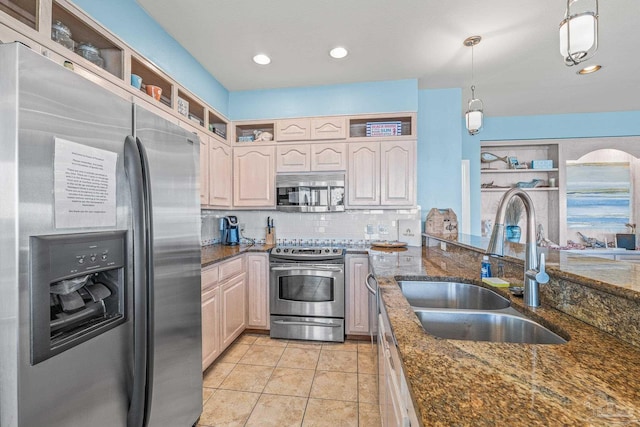 kitchen with stainless steel appliances, hanging light fixtures, sink, and dark stone countertops