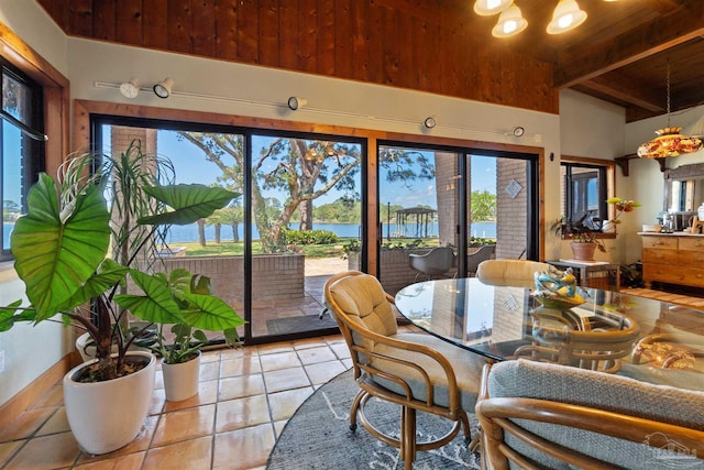 dining room featuring wooden ceiling, light tile patterned flooring, a water view, and beamed ceiling