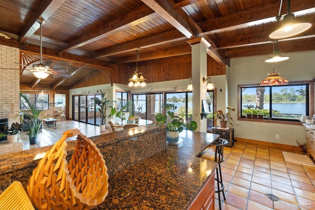 kitchen featuring a healthy amount of sunlight, ceiling fan with notable chandelier, hanging light fixtures, and beamed ceiling