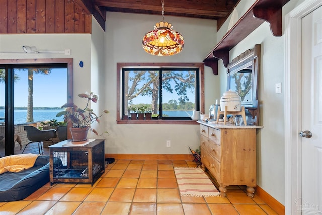 interior space with a water view, light tile patterned floors, and beam ceiling