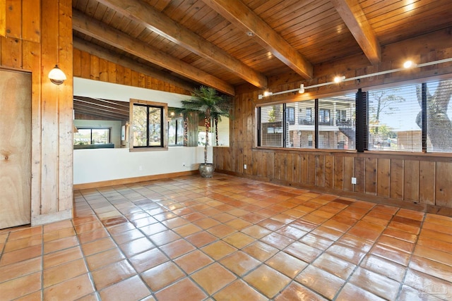 tiled empty room featuring vaulted ceiling with beams, wood walls, and wooden ceiling