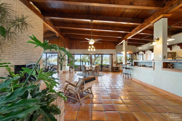 unfurnished living room featuring a fireplace, wooden ceiling, beam ceiling, and ceiling fan